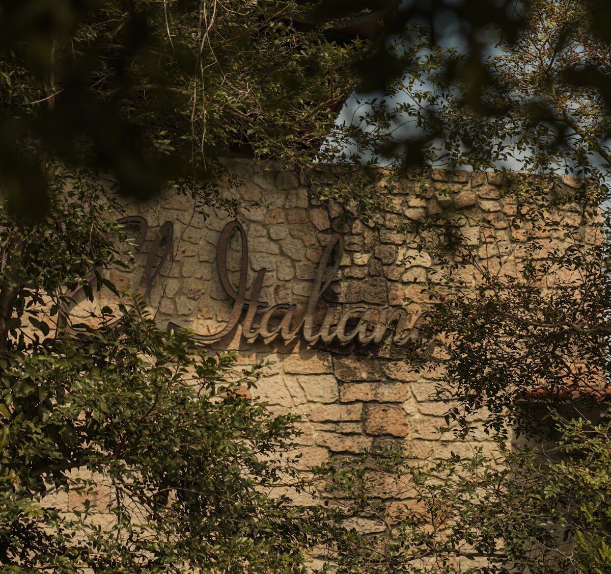 A restaurant's stone signage softened by climbing greenery.