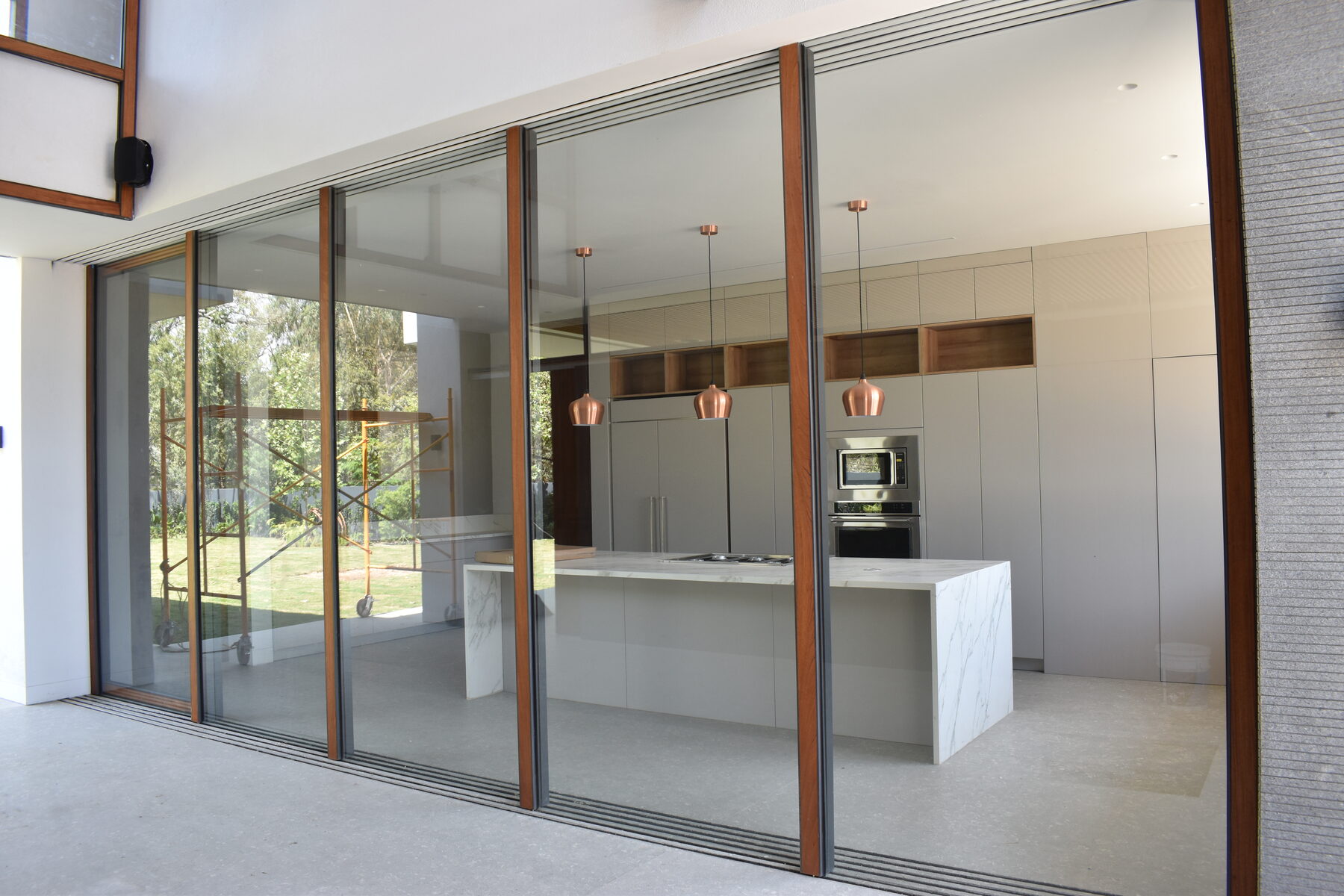 The kitchen island in stone with copper pendants and garden views.