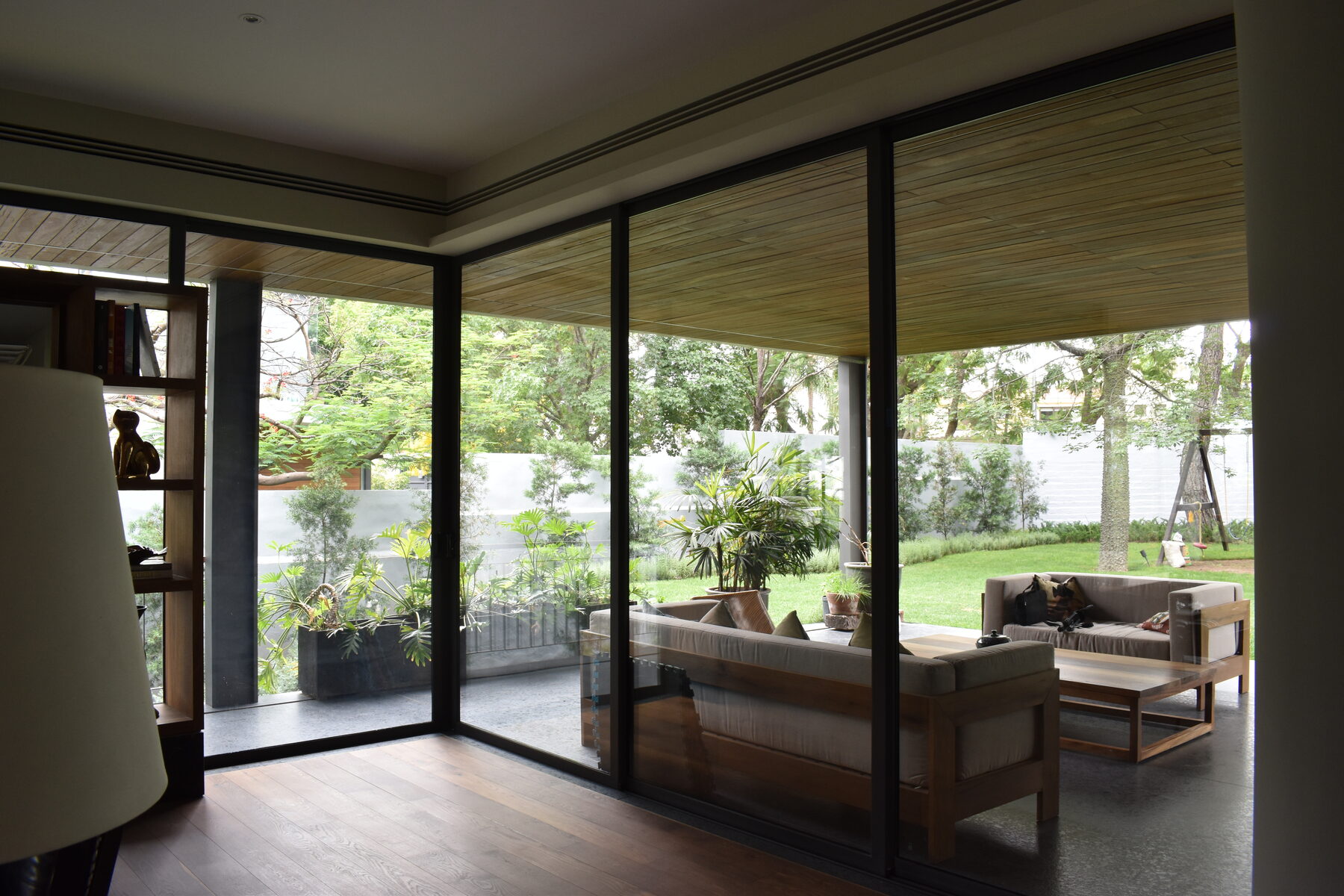 A living area with a low wooden sofa opening to the garden.