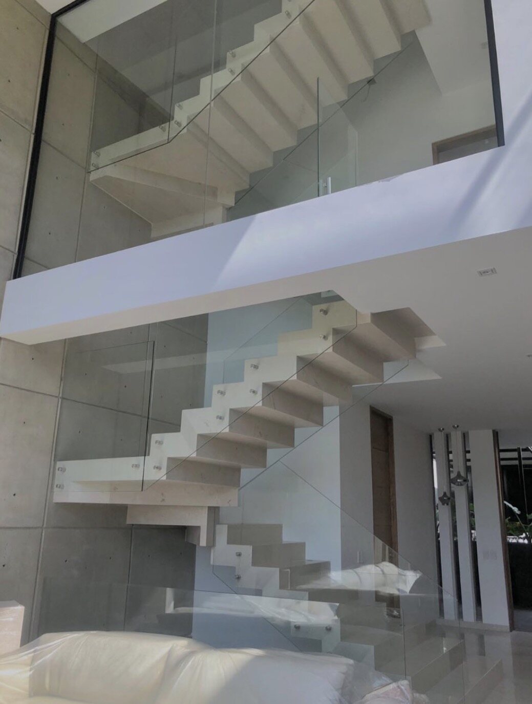 The cantilevered stair against board-formed concrete and glass.