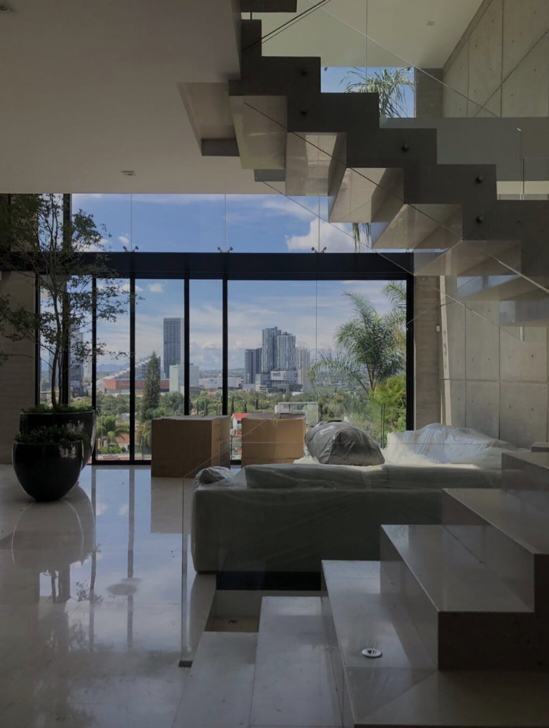 A living room opening through full-height glass to the city skyline.