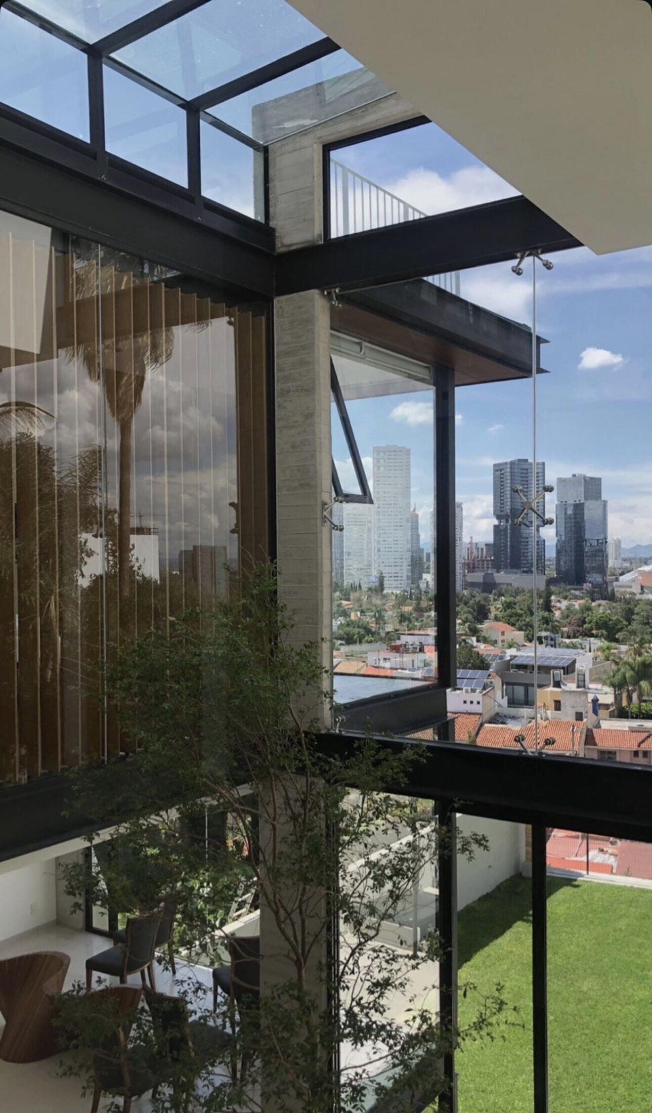 A glazed corner framing the garden and distant city.